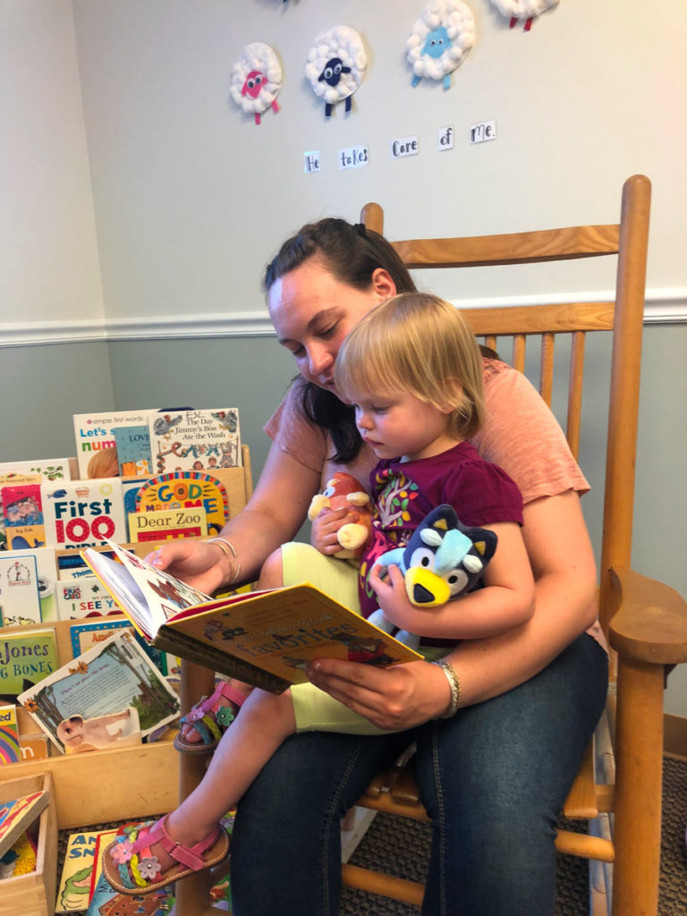 2022 photo of an adult reading to a child in the nursery